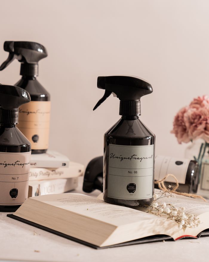 Stylish spray bottles of fragrance with pink flowers and books for a clean, modern aesthetic.
