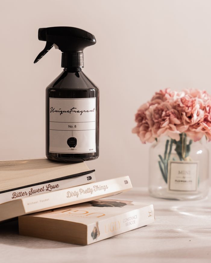 Stylish arrangement of fragrance bottle with books and flowers on a table.