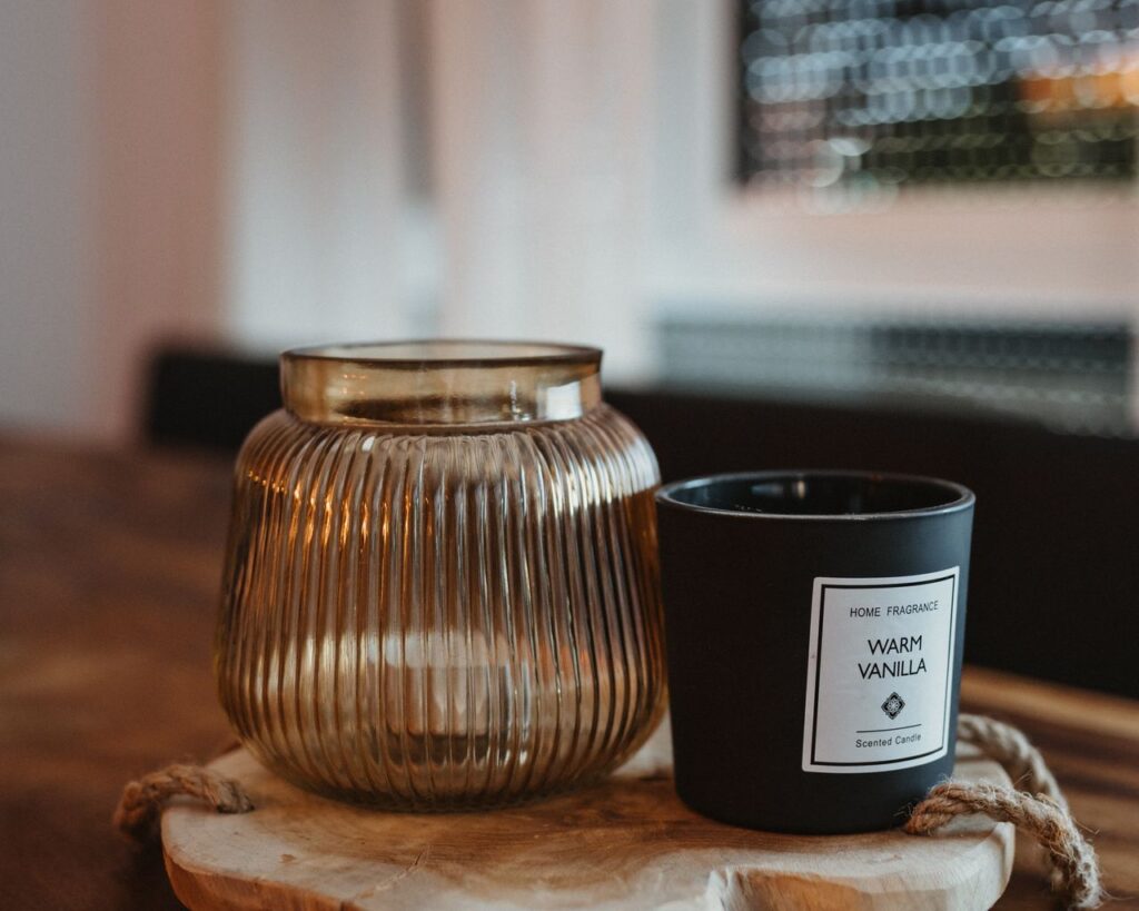 A warm vanilla scented candle in a decorative glass holder on a wooden tray, creating a cozy atmosphere.